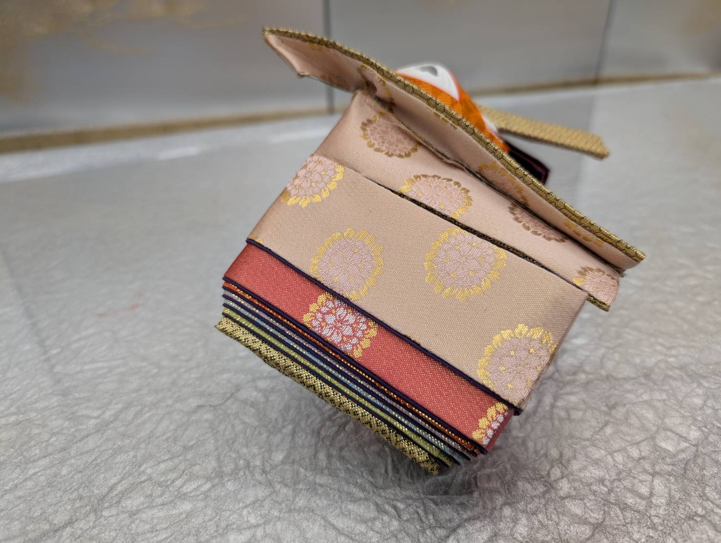 An example costume for the experience: gold and pale pink silk with round crest patterns