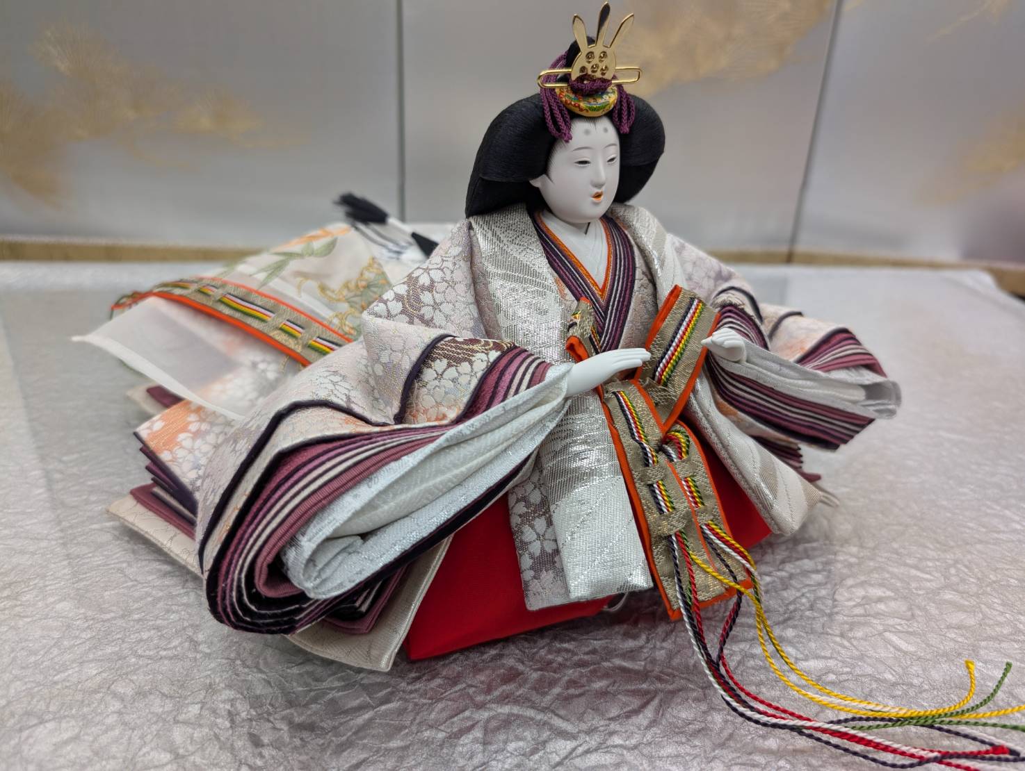 The completed empress hina doll wearing a cherry-blossom silk costume, sitting gracefully
